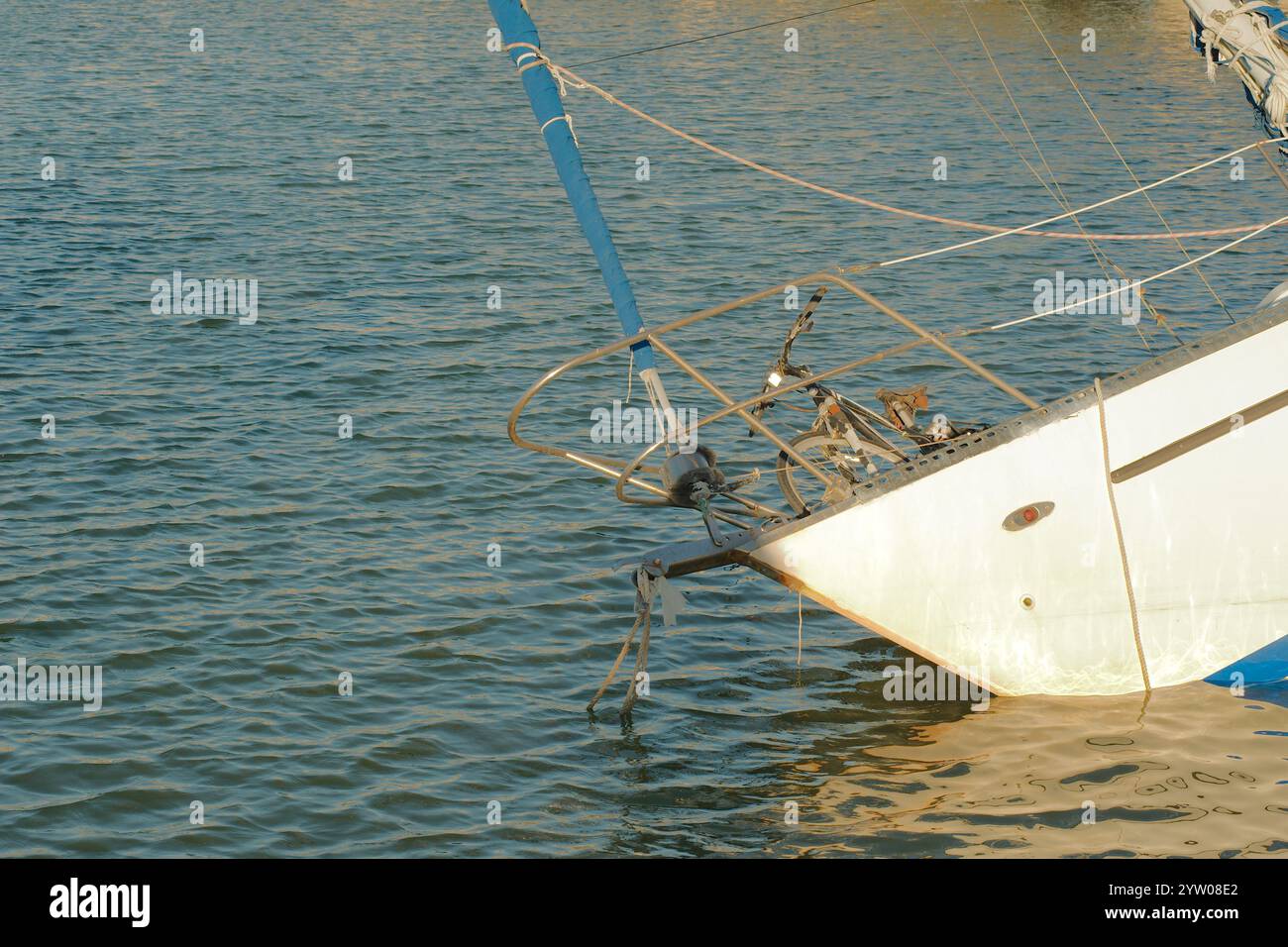 Vista ravvicinata di una barca in rovina con una bicicletta arrugginita sul bordo del concrete Seawall sulla baia di Boca Ciega a St Pete Beach, Florida. Blue Sky e Calm wa Foto Stock