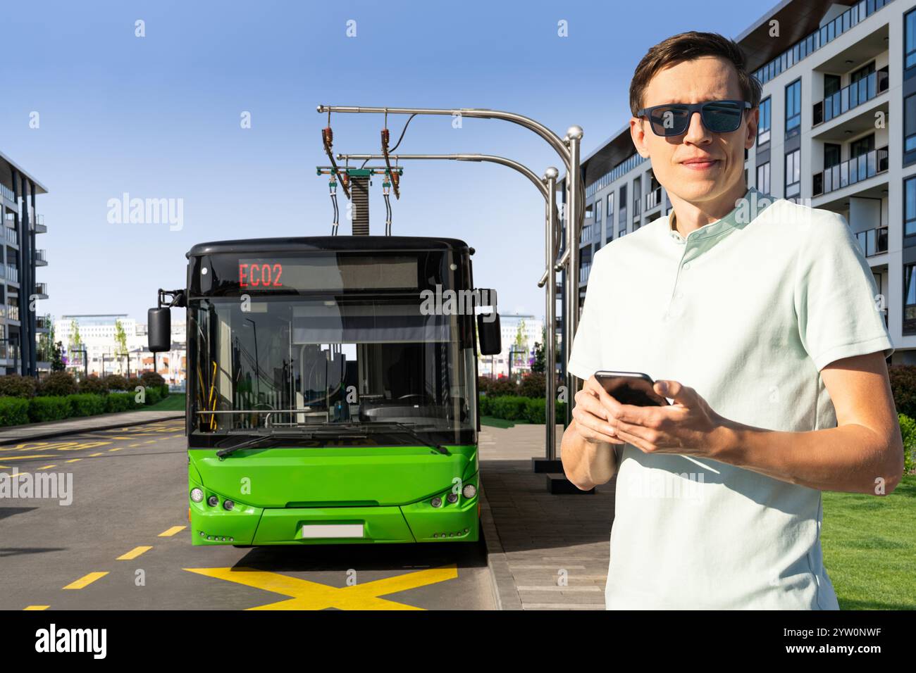 Uomo con smartphone sullo sfondo della ricarica del bus elettrico. Foto Stock