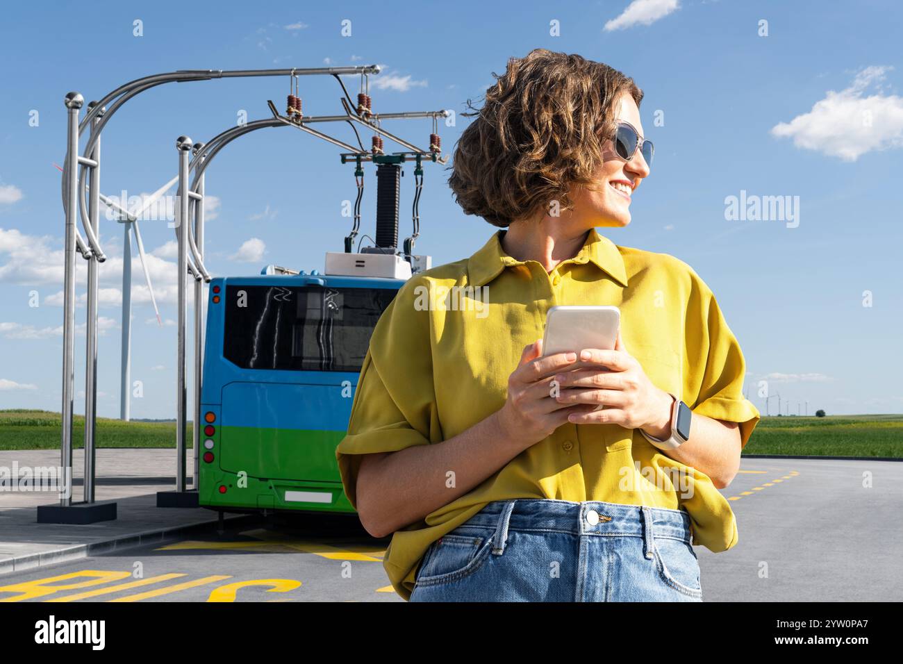 Donna con smartphone sullo sfondo della ricarica del bus elettrico. Foto Stock