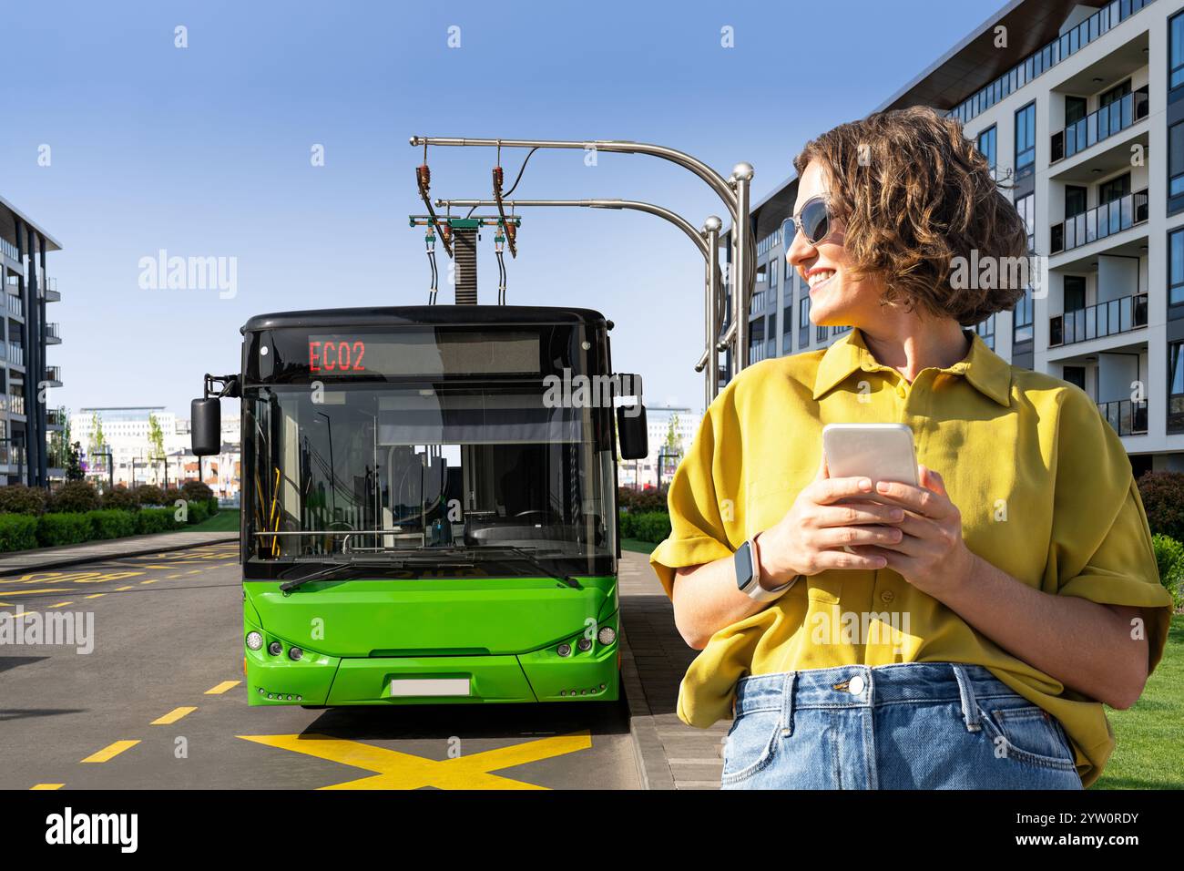 Donna con smartphone sullo sfondo della ricarica del bus elettrico. Foto Stock