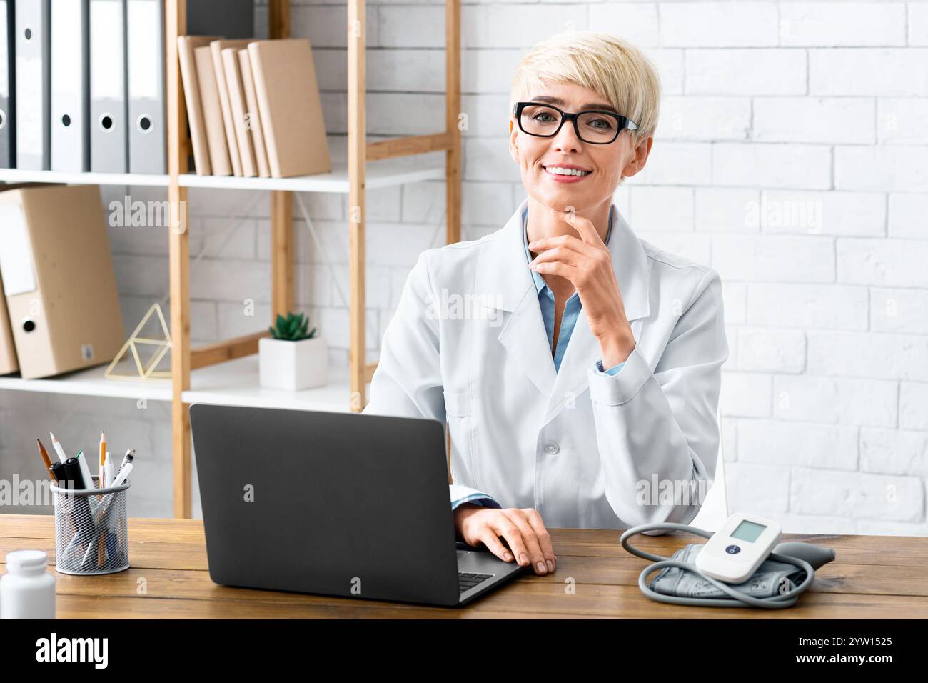 Trattamento accessibile. Donna sorridente dottore seduto al tavolo Foto Stock