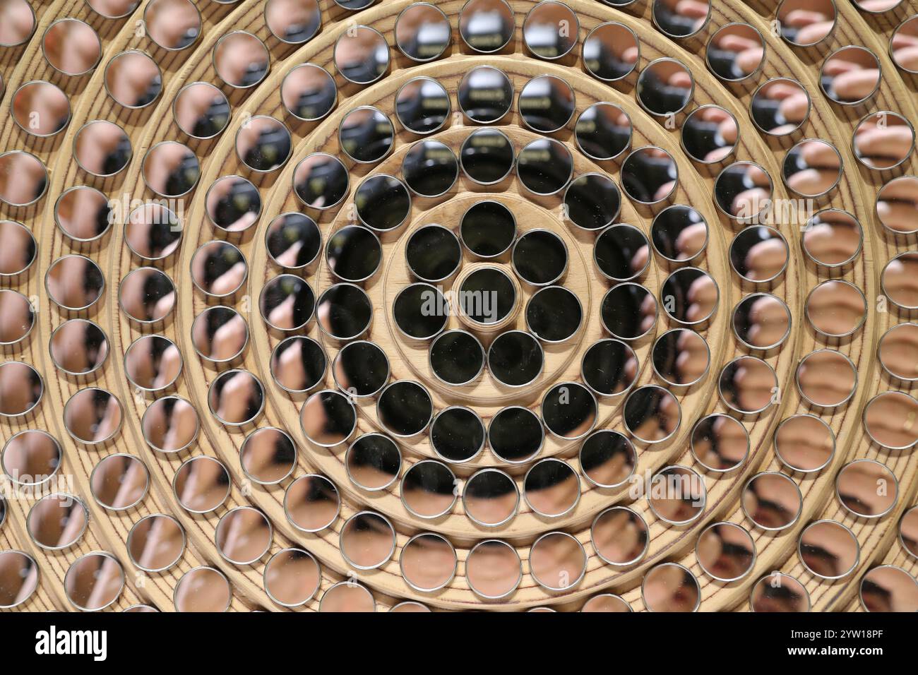 La foto presenta un mosaico artistico composto da specchi rotondi identici disposti concentricamente attorno a uno specchio centrale più grande. Foto Stock