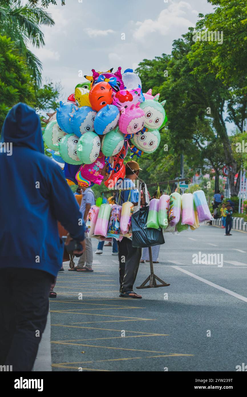 Balikpapan, Indonesia - 9 novembre 2024. Oltre ai palloncini, sta anche vendendo caramelle di cotone. Foto Stock