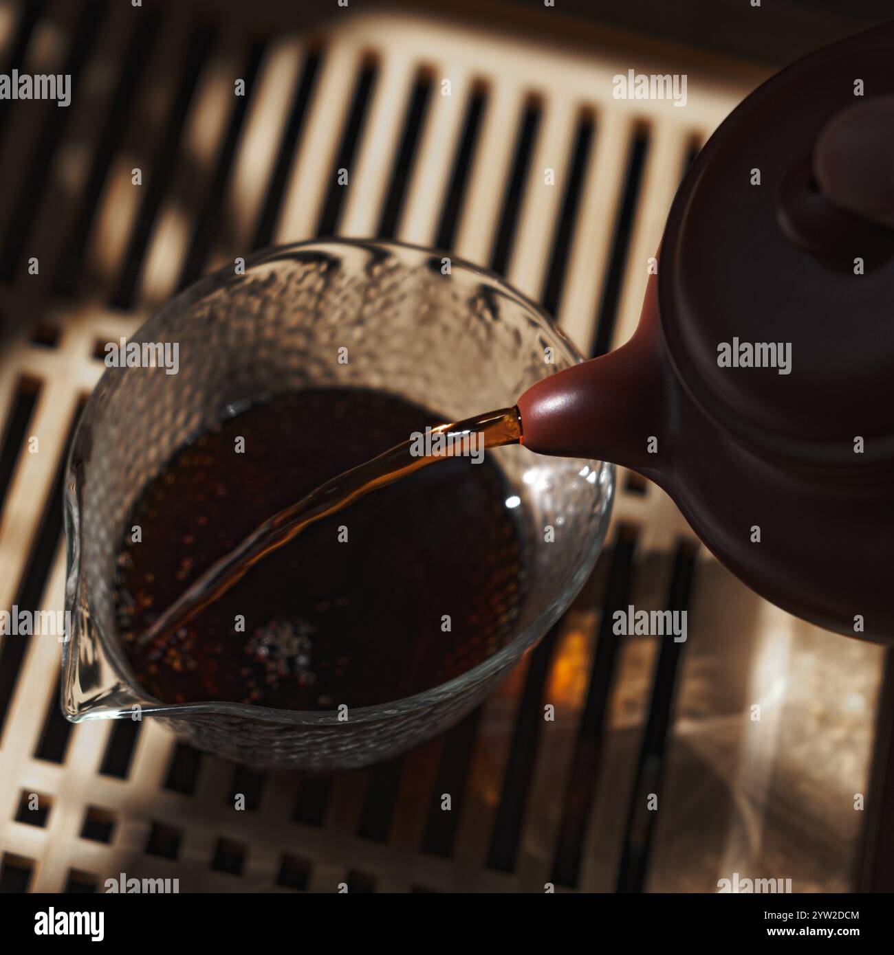 Immergetevi nell'arte tranquilla e tranquilla di versare il tè, splendidamente catturati con un'illuminazione soffusa e calda Foto Stock