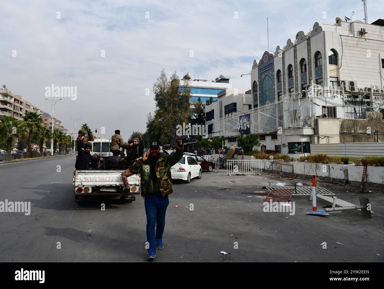 Damasco, Siria. 8 dicembre 2024. Militanti armati si riuniscono fuori dall'ambasciata iraniana a Damasco, in Siria, 8 dicembre 2024. Le forze dell'opposizione armata siriana hanno preso il pieno controllo di Damasco domenica, ponendo fine a oltre cinquant'anni di governo della famiglia Assad. Il ministero degli Esteri russo ha rilasciato una dichiarazione in cui si afferma che il presidente siriano Bashar al-Assad "ha deciso di lasciare il posto presidenziale e ha lasciato il paese, dando istruzioni per trasferire il potere in pace". L'ambasciata iraniana a Damasco è stata assalita da militanti armati. Crediti: Ammar Safarjalani/Xinhua/Alamy Live News Foto Stock