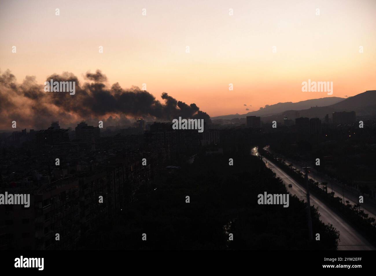 Damasco. 8 dicembre 2024. Questa foto scattata l'8 dicembre 2024 mostra fumo intenso dopo un'esplosione a Damasco, in Siria. Le forze dell'opposizione armata siriana hanno preso il pieno controllo di Damasco domenica, ponendo fine a oltre cinquant'anni di governo della famiglia Assad. Il ministero degli Esteri russo ha rilasciato una dichiarazione in cui si afferma che il presidente siriano Bashar al-Assad "ha deciso di lasciare il posto presidenziale e ha lasciato il paese, dando istruzioni per trasferire il potere in pace". Crediti: Monsef Memari/Xinhua/Alamy Live News Foto Stock