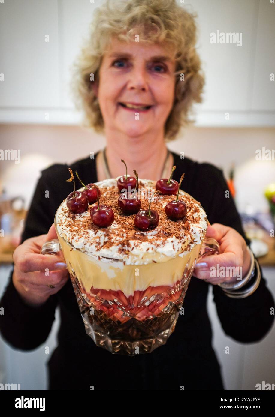 Donna fatta in casa per le festività natalizie con base di budino natalizio, crema pasticcera, prugne, ciliegie e crema fraiche al mascarpone Foto Stock