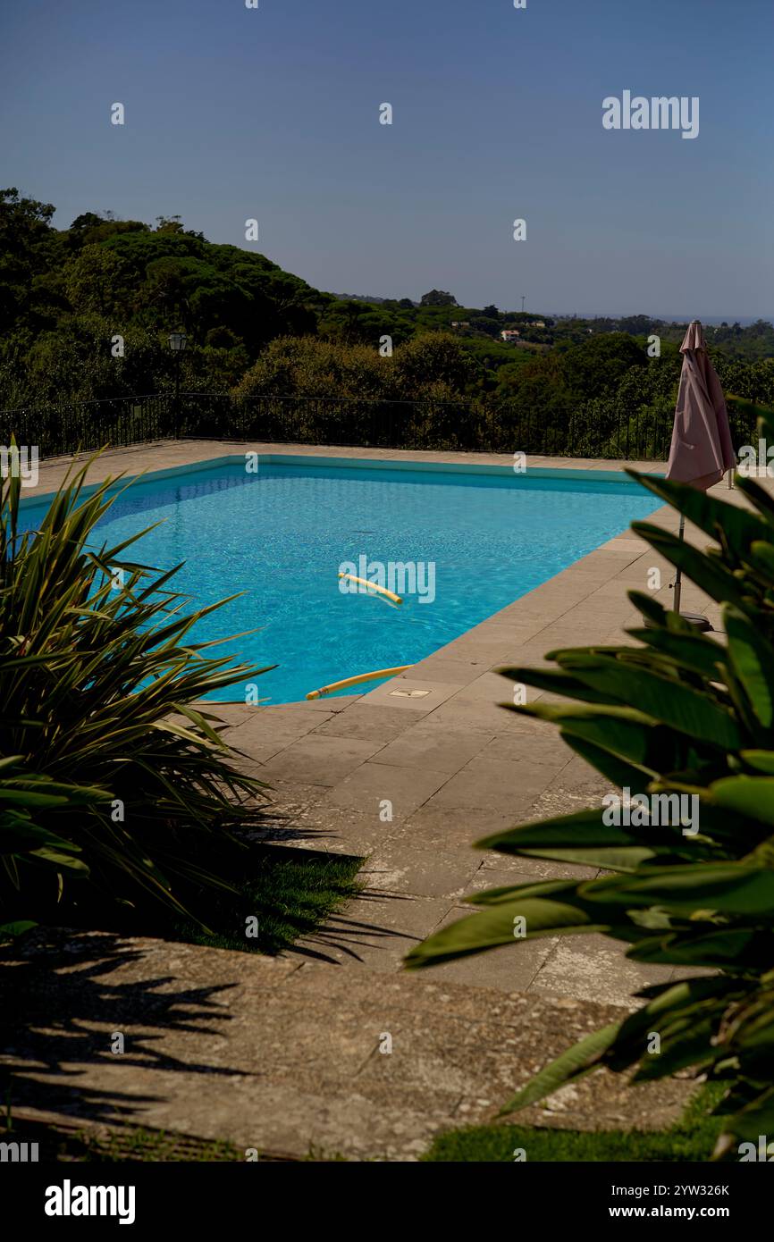 Una piscina all'aperto in una giornata di sole con vegetazione lussureggiante e un cielo blu sullo sfondo, il Portogallo Foto Stock