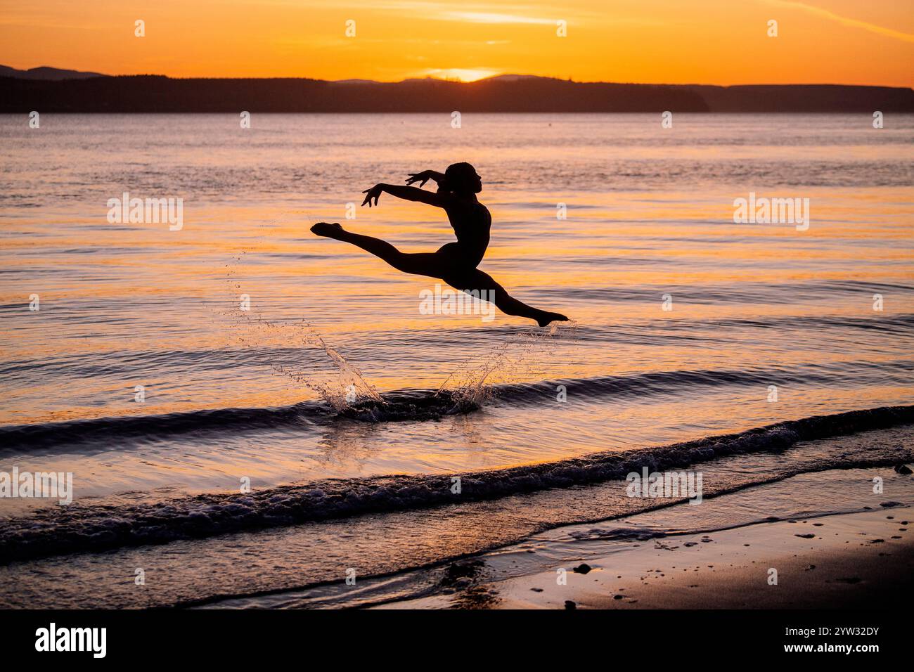 La figura sagomata esegue una mossa di danza a mezz'aria su una spiaggia al tramonto, negli Stati Uniti Foto Stock