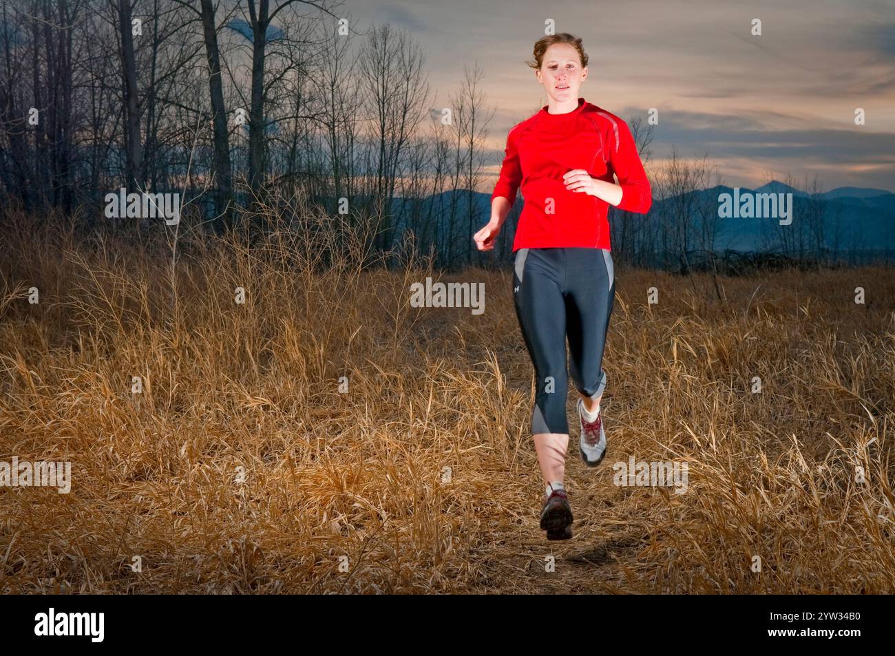 Un sentiero per giovani donne corre al crepuscolo al lago artificiale di Boulder. Boulder, CO. (Riempimento-flash) Foto Stock