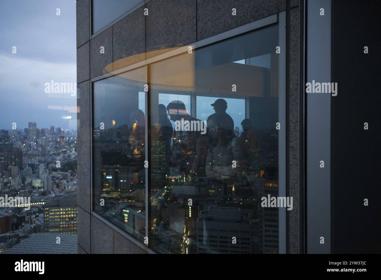 Persone che ammirano lo skyline della città dall'alto, al tramonto, nel grattacielo di Kenzo Tange, riflessi attraverso il vetro, l'edificio del governo cittadino, Tokyo, Foto Stock