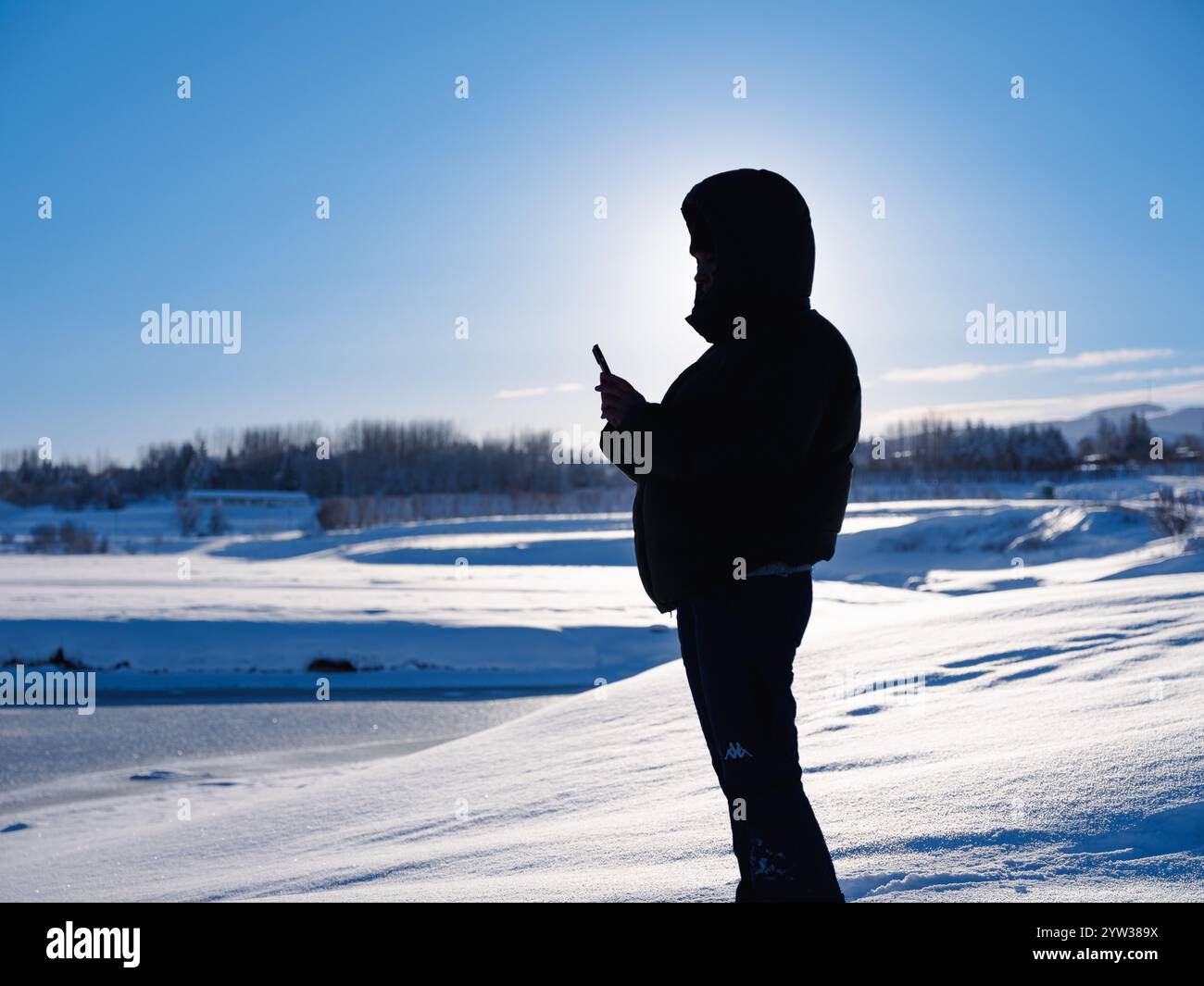 Sagoma di una persona nel paesaggio invernale con un sole tramontante Foto Stock