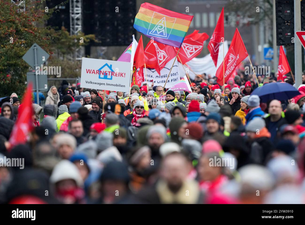 Wolfsburg, Germania. 9 dicembre 2024. I dipendenti VW partecipano a un rally IG Metall di fronte alla sede centrale della Volkswagen durante uno sciopero di avvertimento nello stabilimento principale della casa automobilistica tedesca di Wolfsburg. Sulla targhetta si legge: "Avvertimento sciopero" credito: Martin Meissner/AP POOL/dpa/Alamy Live News Foto Stock
