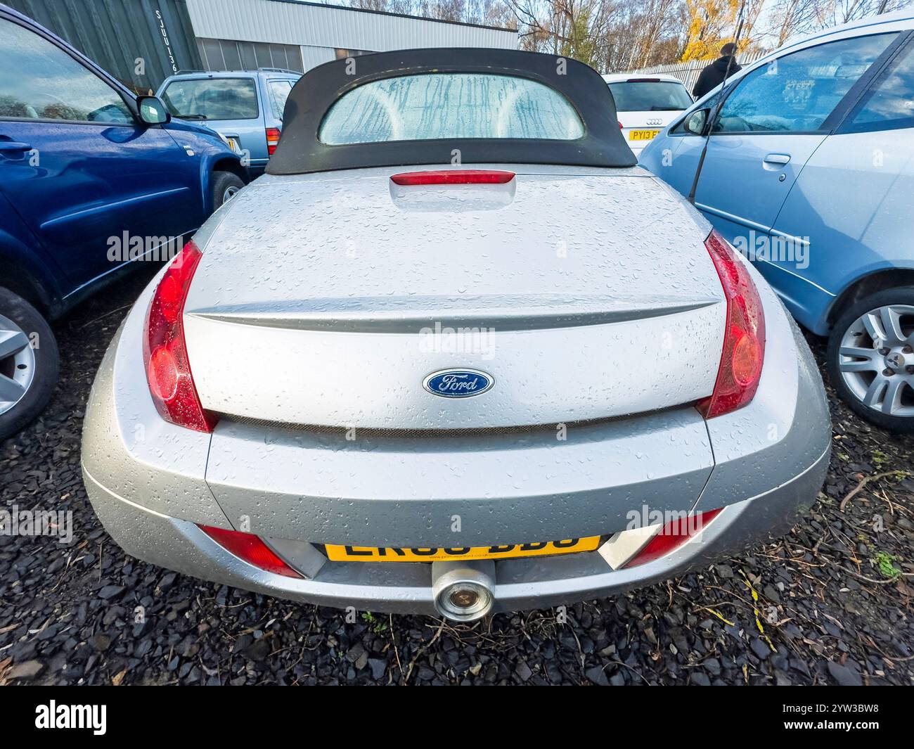 Vista posteriore della Ford KA convertibile compatta color argento parcheggiata su un terreno ghiaioso tra gli altri veicoli in una giornata nuvolosa Foto Stock