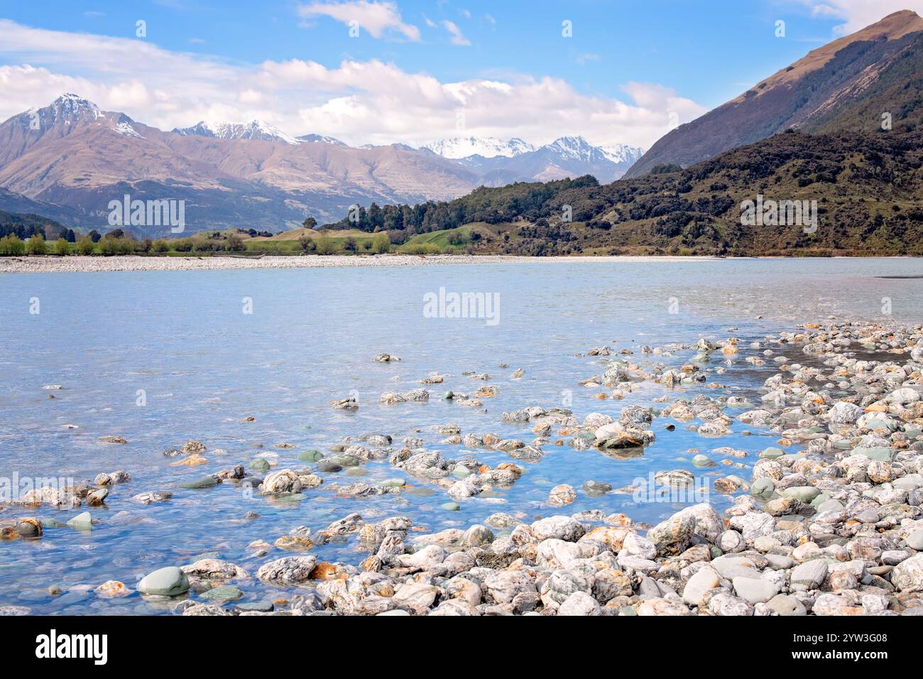 Fiume DART con coste rocciose, vie d'acqua intrecciate alimentate da ghiacciai, montagne innevate in lontananza, nuova Zelanda Foto Stock