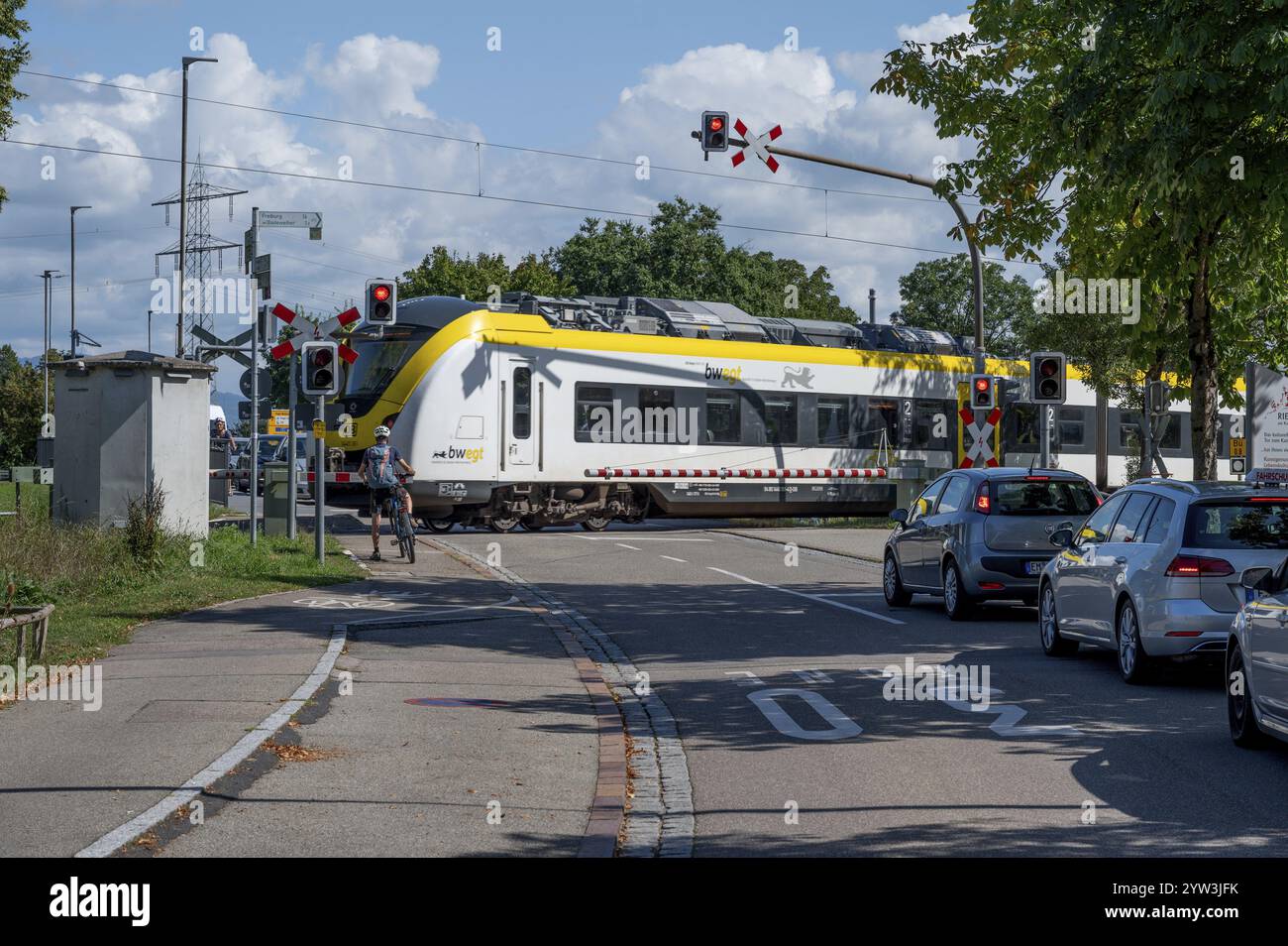 Treno regionale che attraversa un passaggio a livello con barriere, Riegel am Kaiserstuhl, Baden-Wuerttemberg, Germania, Europa Foto Stock