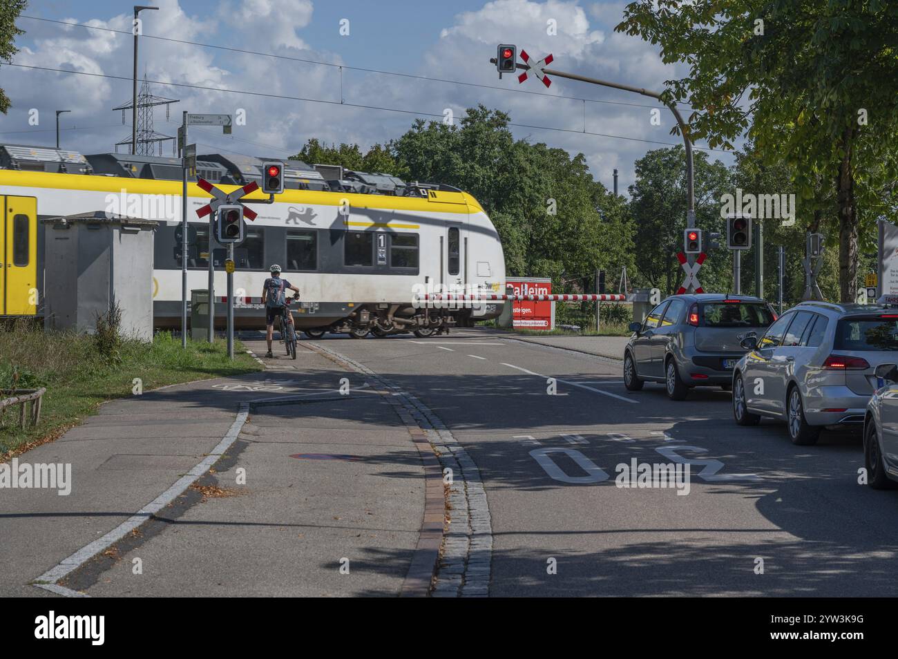 Treno regionale che attraversa un passaggio a livello con barriere, Riegel am Kaiserstuhl, Baden-Wuerttemberg, Germania, Europa Foto Stock