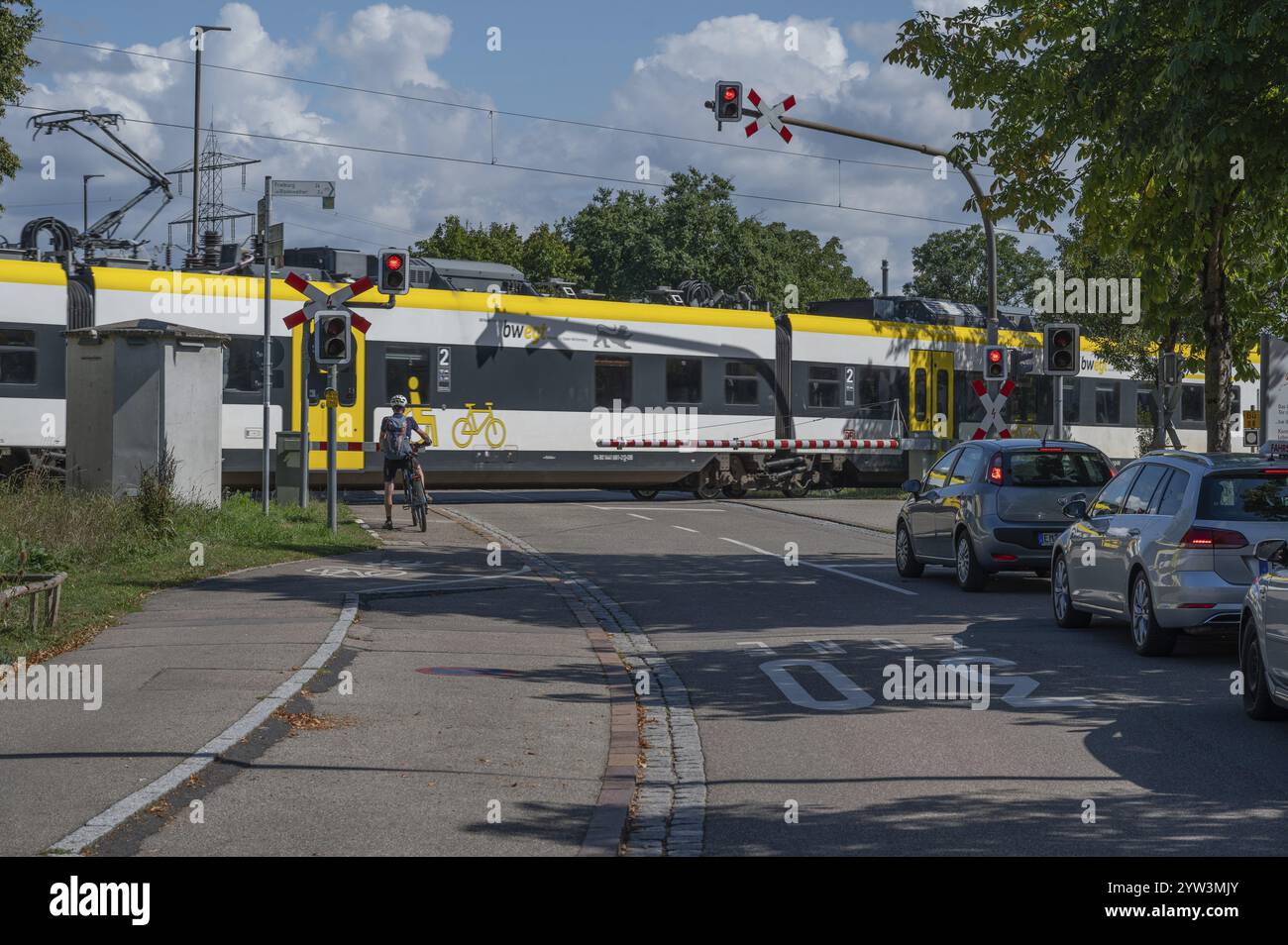 Treno regionale che attraversa un passaggio a livello con barriere, Riegel am Kaiserstuhl, Baden-Wuerttemberg, Germania, Europa Foto Stock