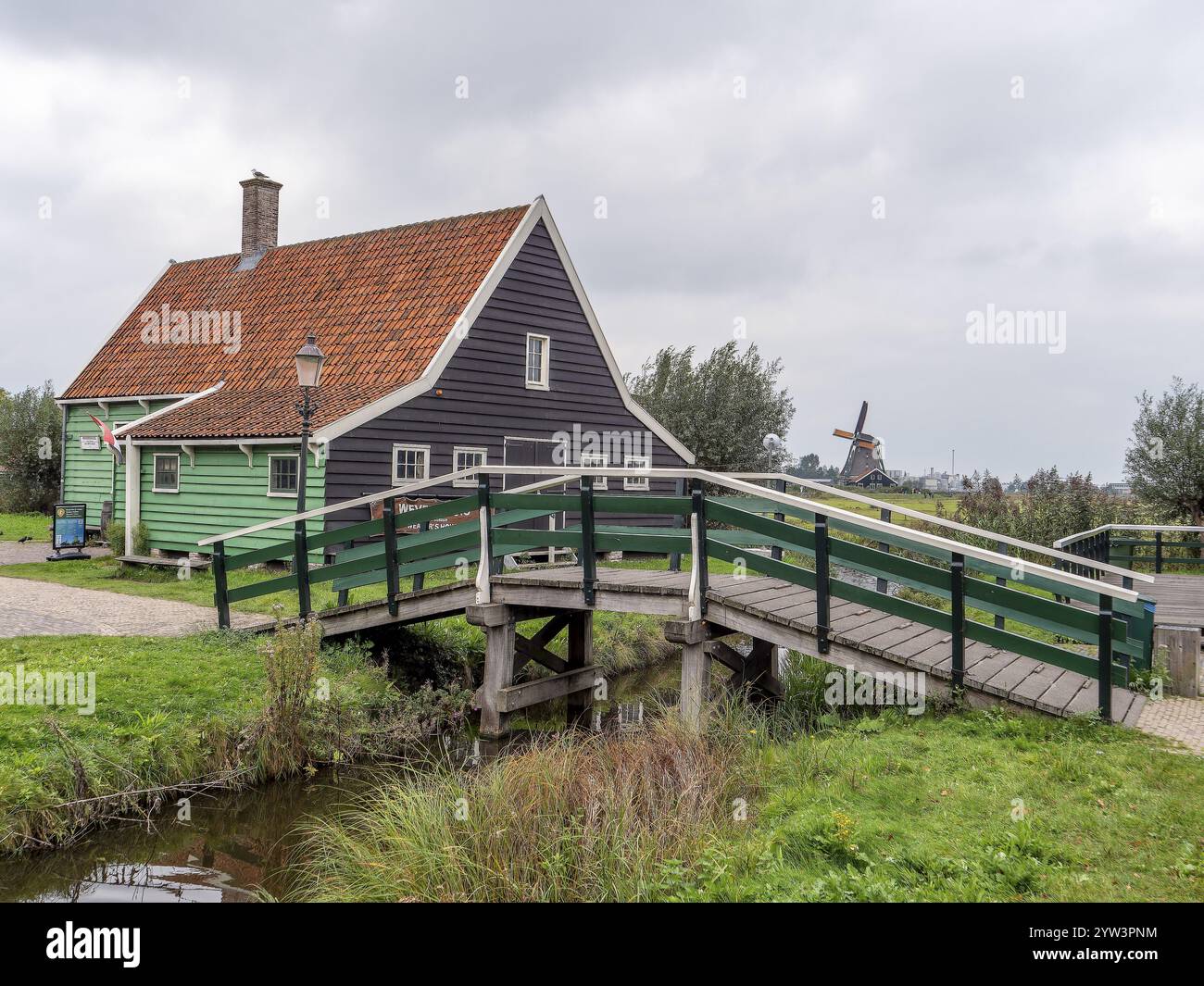 Edificio tradizionale con ponte nel villaggio museo, il museo all'aperto di Zaanse Schans e i tradizionali mulini a vento sullo sfondo, Zaanse Schans, Zaandam Foto Stock