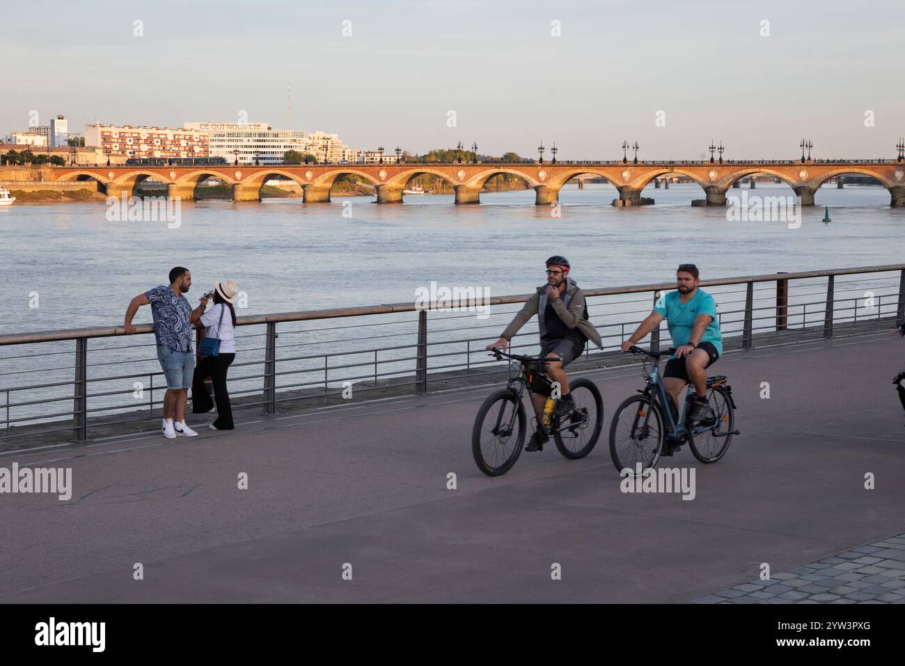 Pont de Pierre ponte sul fiume Garonna con ciclisti lungo il lungomare in serata, Bordeaux, Nouvelle-Aquitaine, Francia, Europa Foto Stock