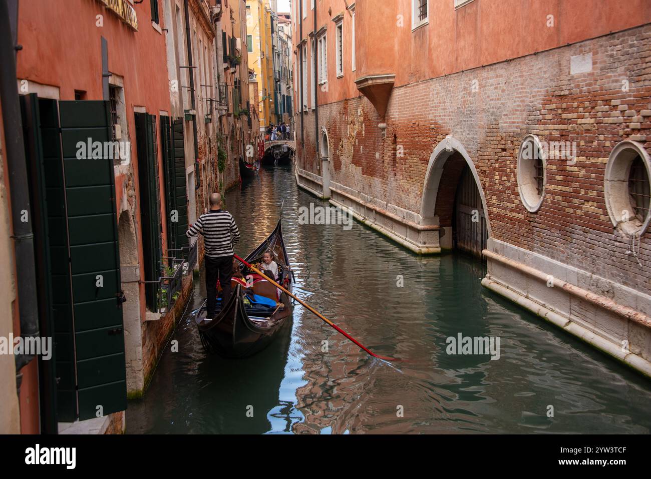 Venezia classica per i turisti: Una gondola trainata da un gondoliere in uno dei tanti canali più piccoli, i cosiddetti "rios", che attraversano il centro storico. A causa della costante umidità, la maggior parte dei vecchi edifici hanno un aspetto piuttosto romantico, a volte morboso. Il centro storico di Venezia è patrimonio dell'umanità dell'UNESCO. Foto Stock