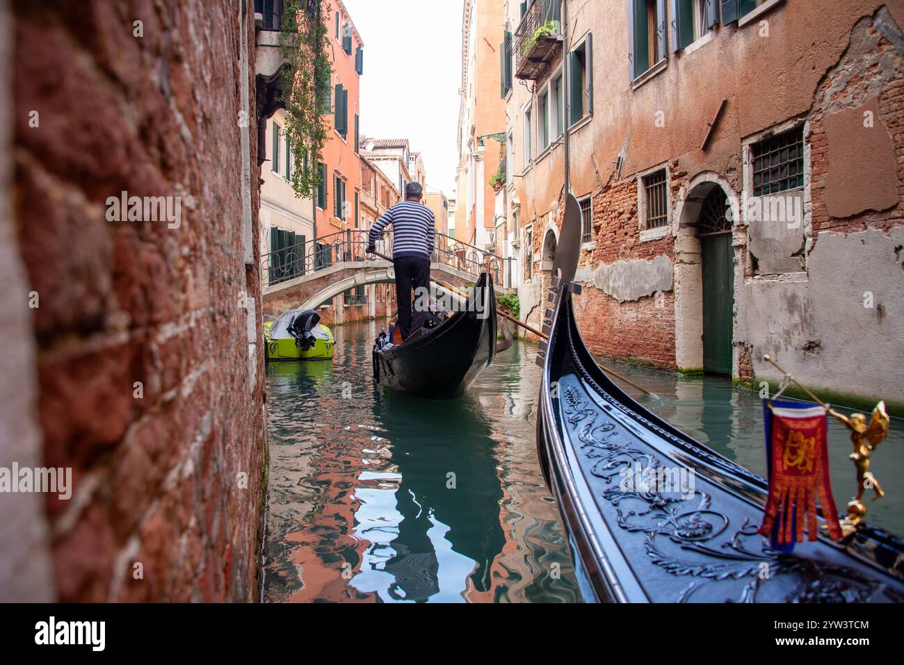 Venezia classica per i turisti: Una gondola trainata da un gondoliere in uno dei tanti canali più piccoli, i cosiddetti "rios", che attraversano il centro storico. A causa della costante umidità, la maggior parte dei vecchi edifici hanno un aspetto piuttosto romantico, a volte morboso. Il centro storico di Venezia è patrimonio dell'umanità dell'UNESCO. Foto Stock