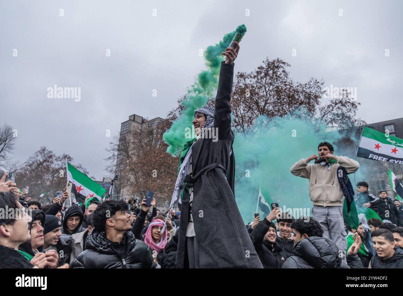 Berlino, Germania. 8 dicembre 2024. Una donna regge una bomba fumogena verde durante i festeggiamenti. I siriani che vivono a Berlino celebrano la caduta del regime di Assad dopo una guerra civile dal 2011. (Foto di Nicholas Muller/SOPA Images/Sipa USA) credito: SIPA USA/Alamy Live News Foto Stock