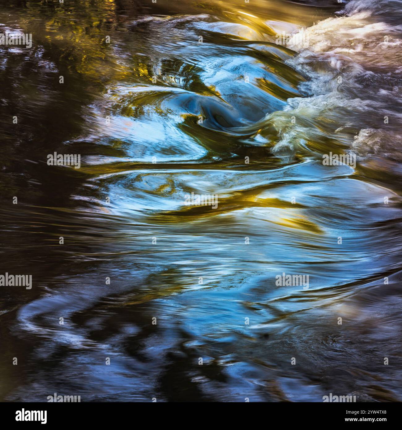 L'acqua fluente del fiume crea ipnotici schemi di luce e ombra, riflettendo la luce solare e gli alberi in un movimento sfocato. Fiume Aterno, abruzzo Foto Stock