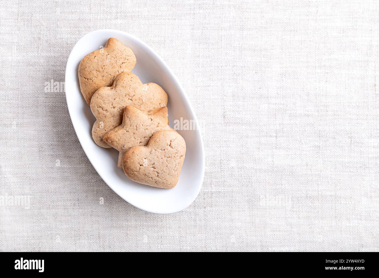 Biscotti fatti in casa con pan di zenzero in un recipiente bianco ovale su lino con spazio vuoto per il testo. Prodotti da forno dolci, di colore marrone chiaro e piatti per il periodo natalizio. Foto Stock