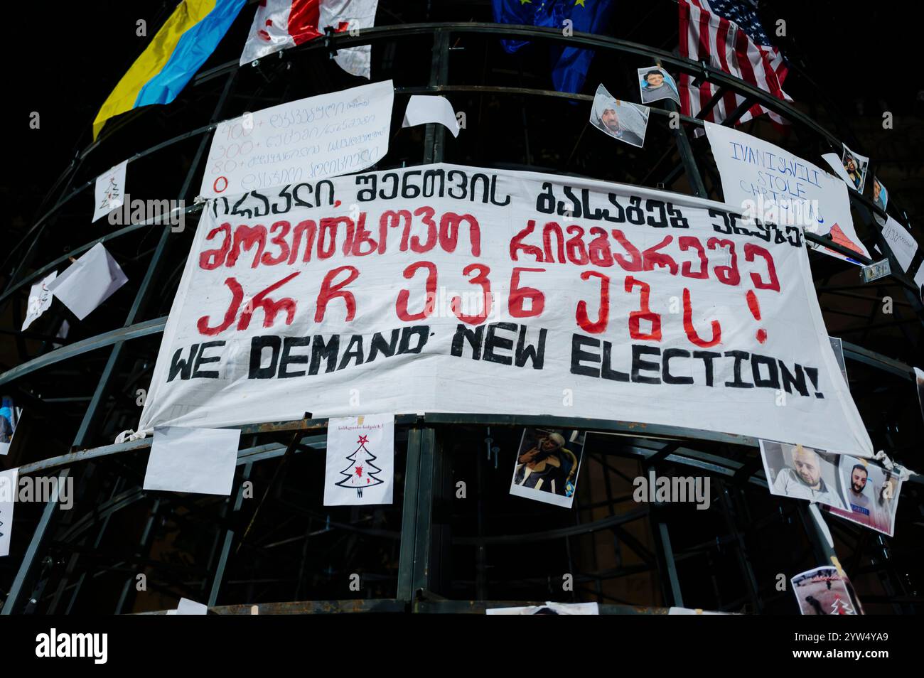 Jan Schmidt-Whitley/le Pictorium - manifestazione dell'opposizione a Tbilisi - 09/12/2024 - Georgia (Europa)/Tbilisi/Tbilisi - Banner con richiesta di nuove elezioni. I manifestanti contrari alla svolta filo-russa del governo di Irakli Kobakhidze stanno ora pattugliando le periferie dei raduni per contrastare gli attacchi da parte delle "titushka" (ausiliari civili pagati dal governo per attaccare e terrorizzare gli avversari). Nelle ultime due settimane i manifestanti si sono riuniti di fronte al Parlamento georgiano ogni sera, mentre le forze di sicurezza usano regolarmente gas lacrimogeni e cannoni ad acqua per disperdere il corvo Foto Stock