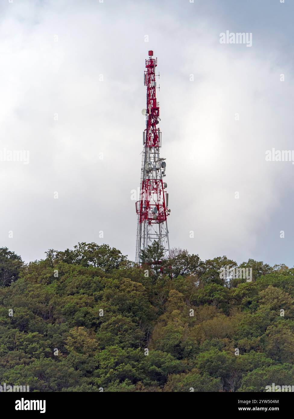 Array di antenne direzionali su una torre di comunicazione rossa e bianca contro il cielo. Foto Stock