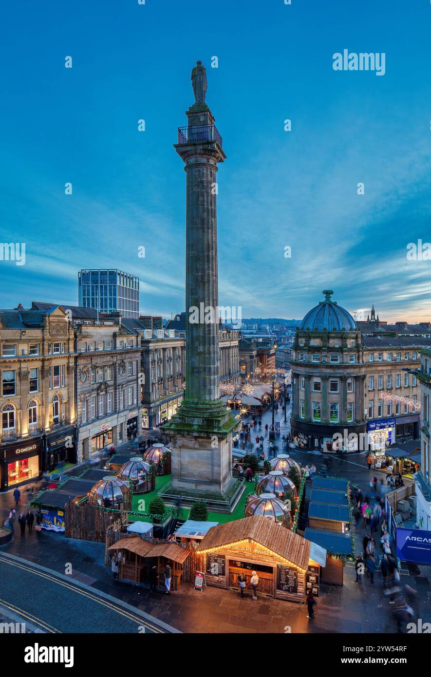 Vista al crepuscolo durante il periodo natalizio guardando il Grey's Monument a Newcastle upon Tyne verso il mercatino di natale con le luci natalizie Foto Stock