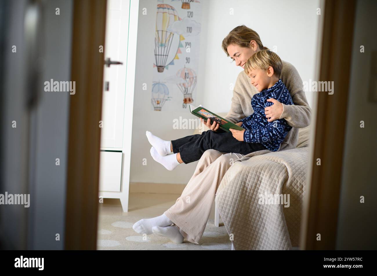 Il bambino e la madre stanno leggendo un libro di storie in una stanza Foto Stock