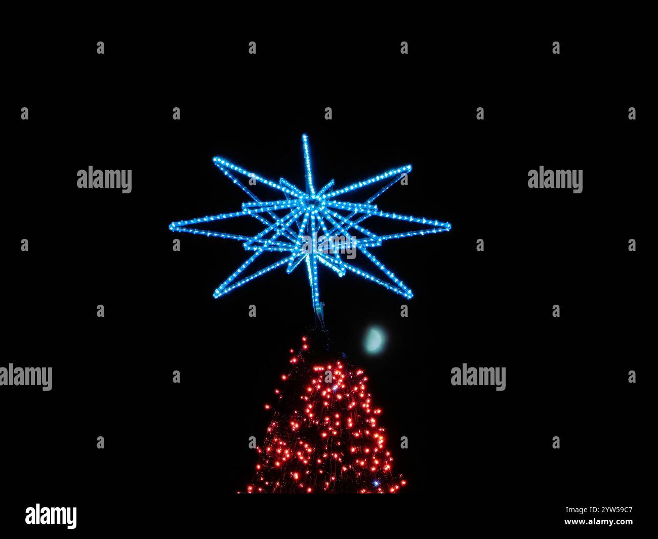 Glow festivo: Albero di Natale con il fiocco di neve. Apparecchi di illuminazione artificiale e luce naturale lunare . Isolato su sfondo scuro. Foto Stock