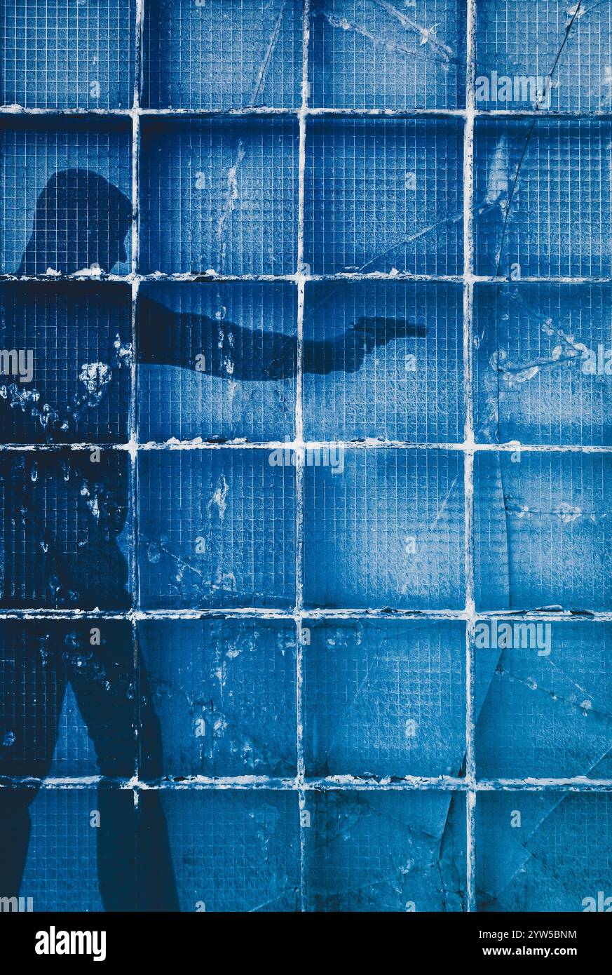 Uomo che indossa una pistola con cappuccio dietro la porta di vetro rotta Foto Stock