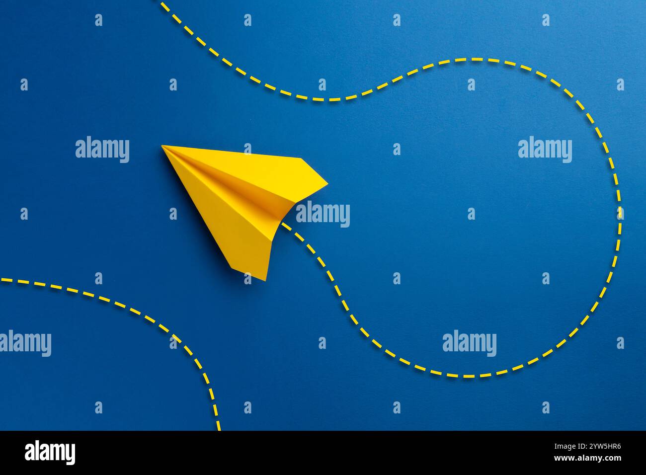 Piano di carta giallo con traiettoria di volo su sfondo blu. Linea tratteggiata per la traiettoria Foto Stock