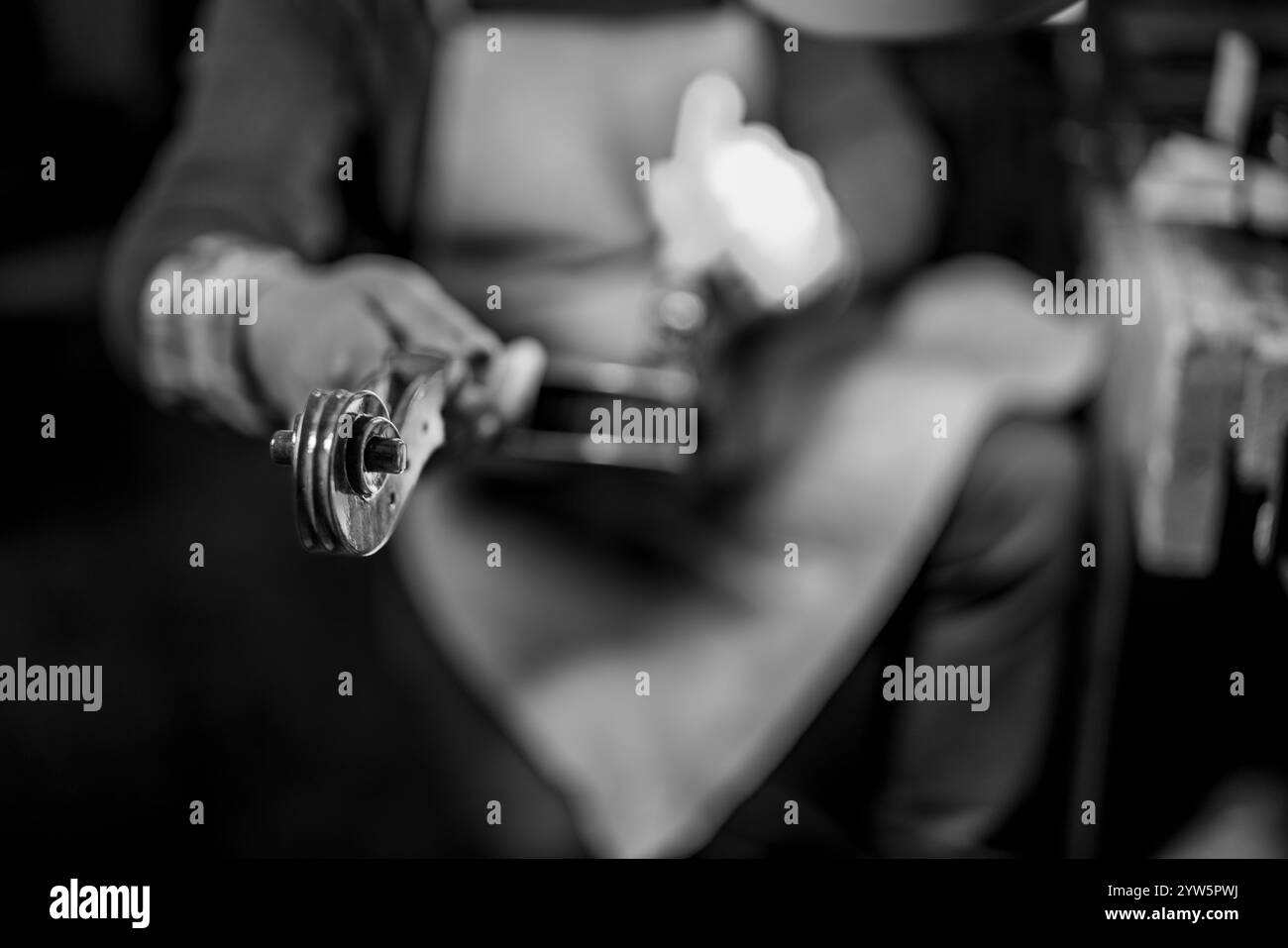 Liutaio che lavora su un rotolo di violino e sui perni di sintonizzazione nel suo laboratorio Foto Stock