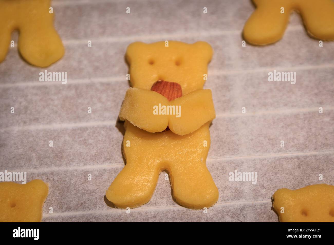 Adorabili biscotti di zucchero fatti in casa a forma di orso che tengono una mandorla tra le zampe su una teglia da forno, pronti per il forno, per le feste natalizie Foto Stock