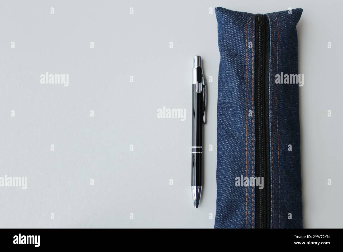 Astuccio a penna in tessuto denim e penna a sfera su sfondo bianco. Forniture per ufficio, cancelleria, università, concetto di ritorno a scuola. Foto Stock