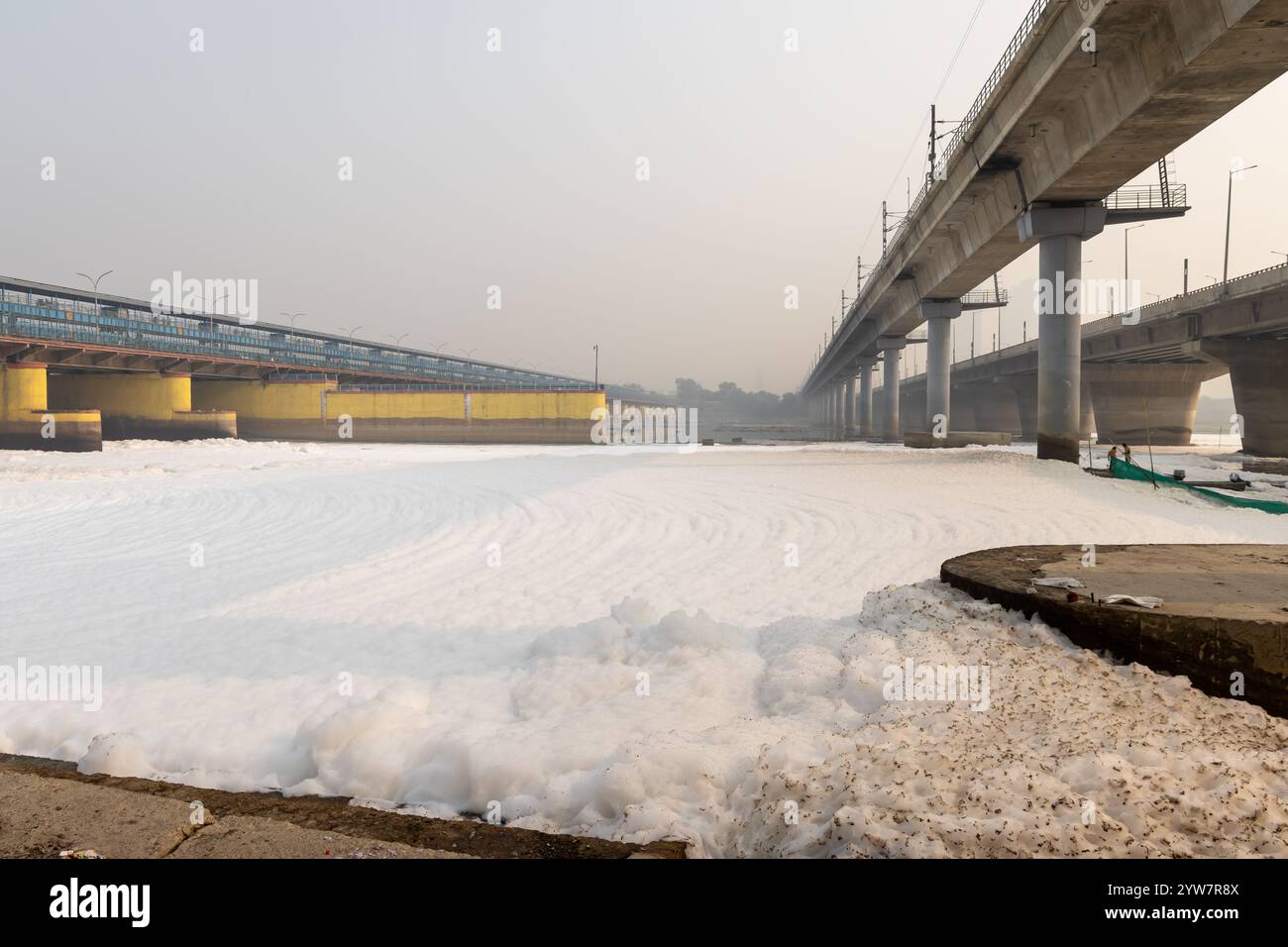 fiume inquinato con effluenti industriali e domestici schiuma tossica e ponte stradale al mattino l'immagine viene scattata presso lo sbarramento del fiume yamuna di okhla delhi india. Foto Stock