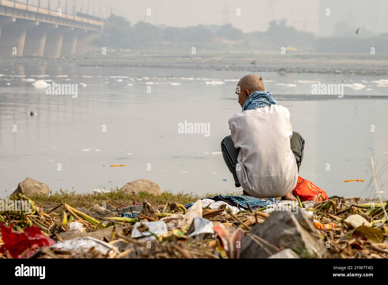 L'uomo isolato che guarda il fiume inquinato con schiuma tossica al mattino viene scattato presso lo sbarramento di okhla del fiume yamuna, delhi, india. Foto Stock