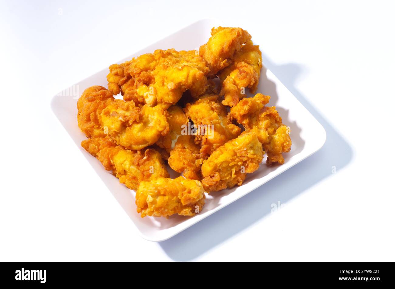 Croccanti pepette di pollo fritte su un piatto di ceramica bianca Foto Stock