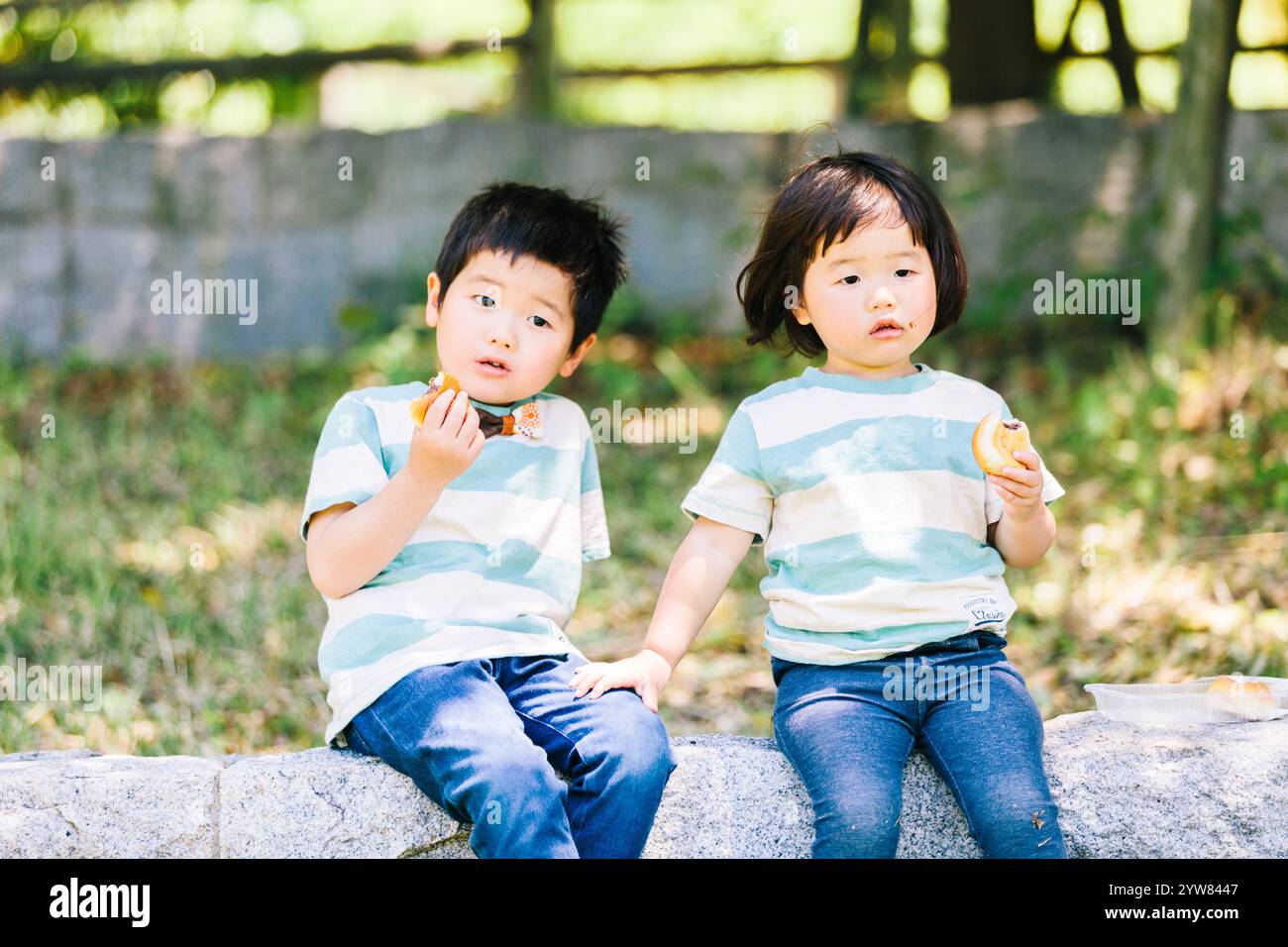 Ragazzo e ragazza mangiano pane all'ombra di un albero Foto Stock