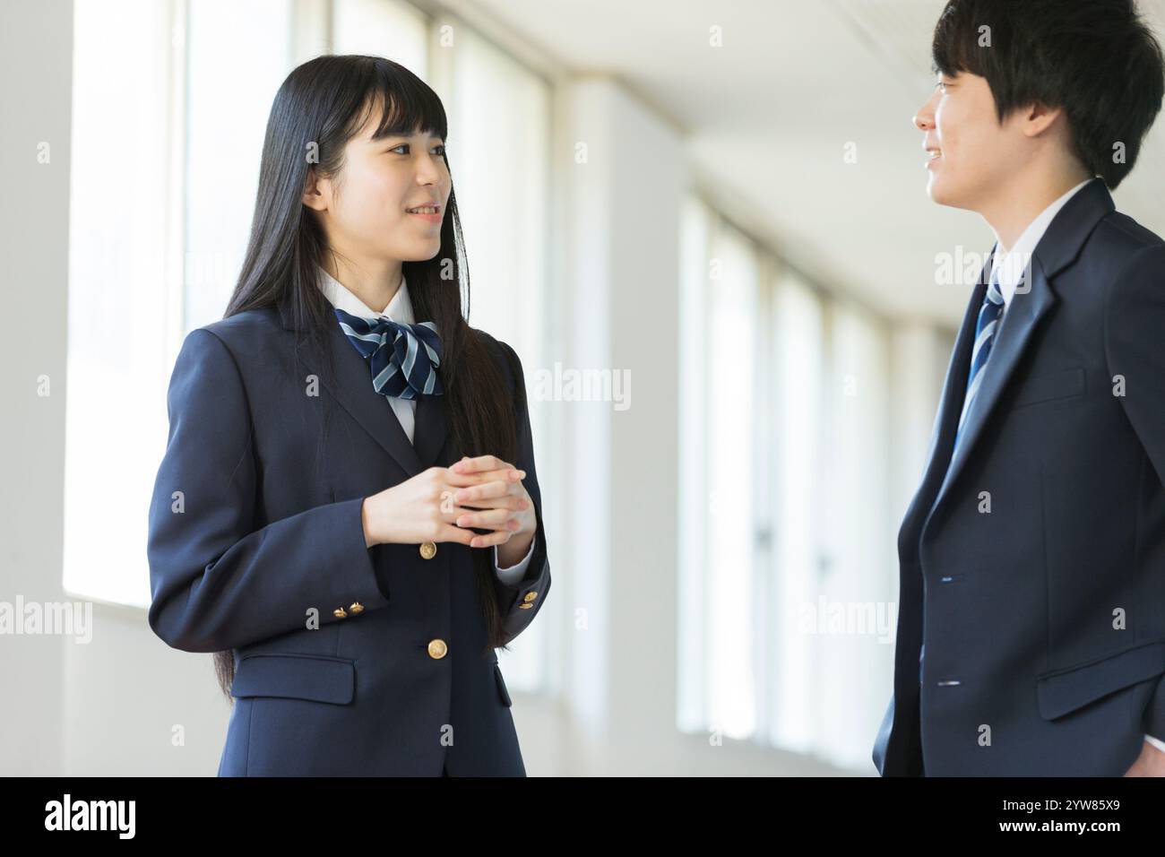 Studenti delle superiori uomini e donne che parlano in corridoio Foto Stock
