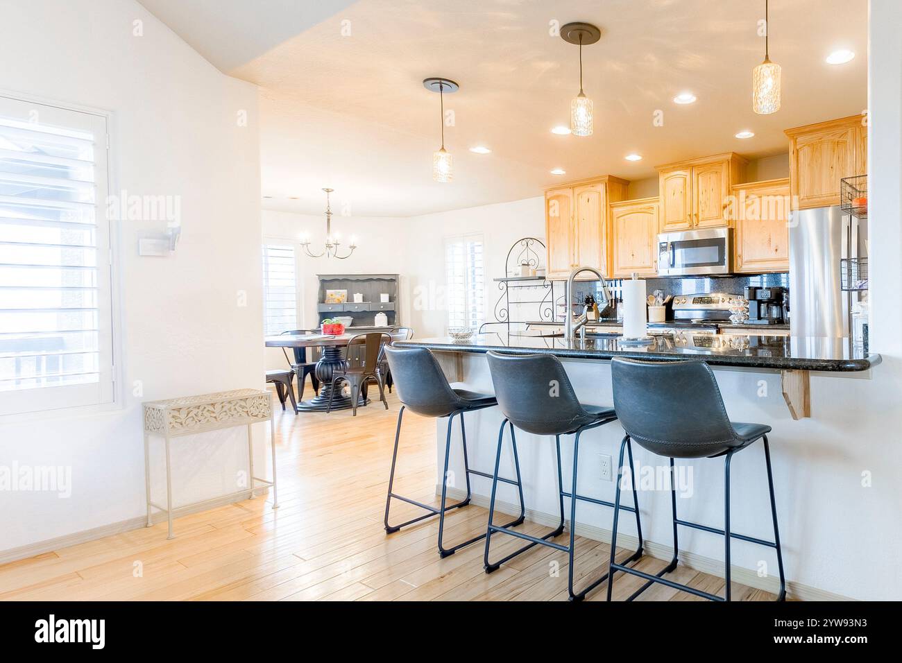 Cucina moderna e zona pranzo con armadi in legno ed eleganti sgabelli da bar che presentano interni dal design contemporaneo Foto Stock