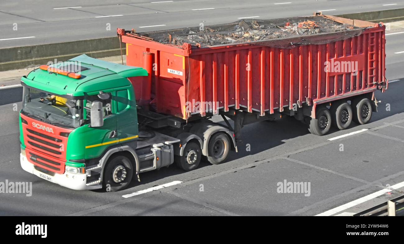 Green Scania hgv, fornitore di servizi di trasporto senza attrezzatura, che traina il carico del contenitore del coperchio della rete del semirimorchio con tetto aperto rosso, rifiuti generici, guida su strada autostradale M25 Inghilterra, regno unito Foto Stock