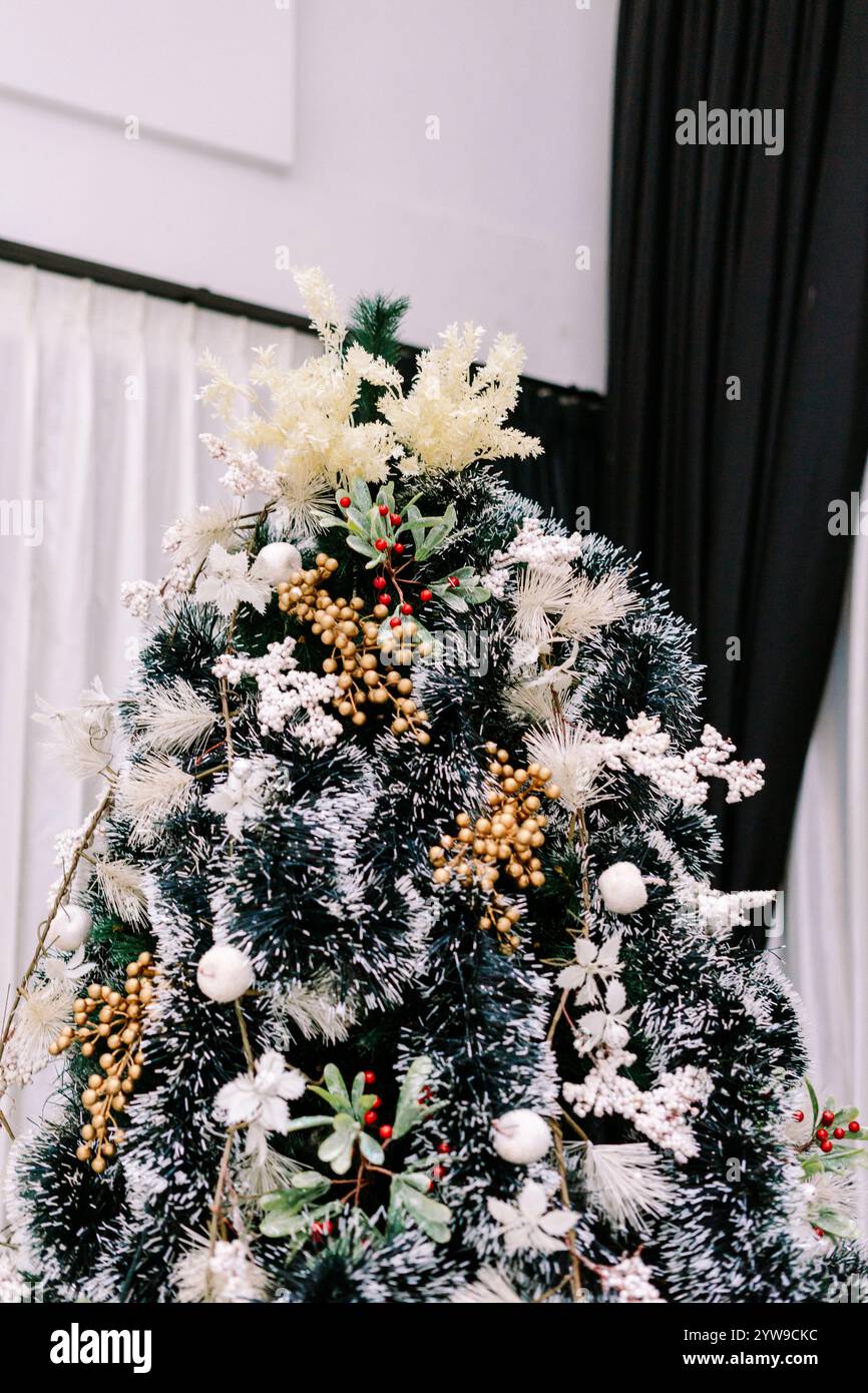 Un albero di Natale splendidamente decorato con ornamenti vibranti e luci scintillanti, che creano un'atmosfera festosa e gioiosa per le festività natalizie Foto Stock