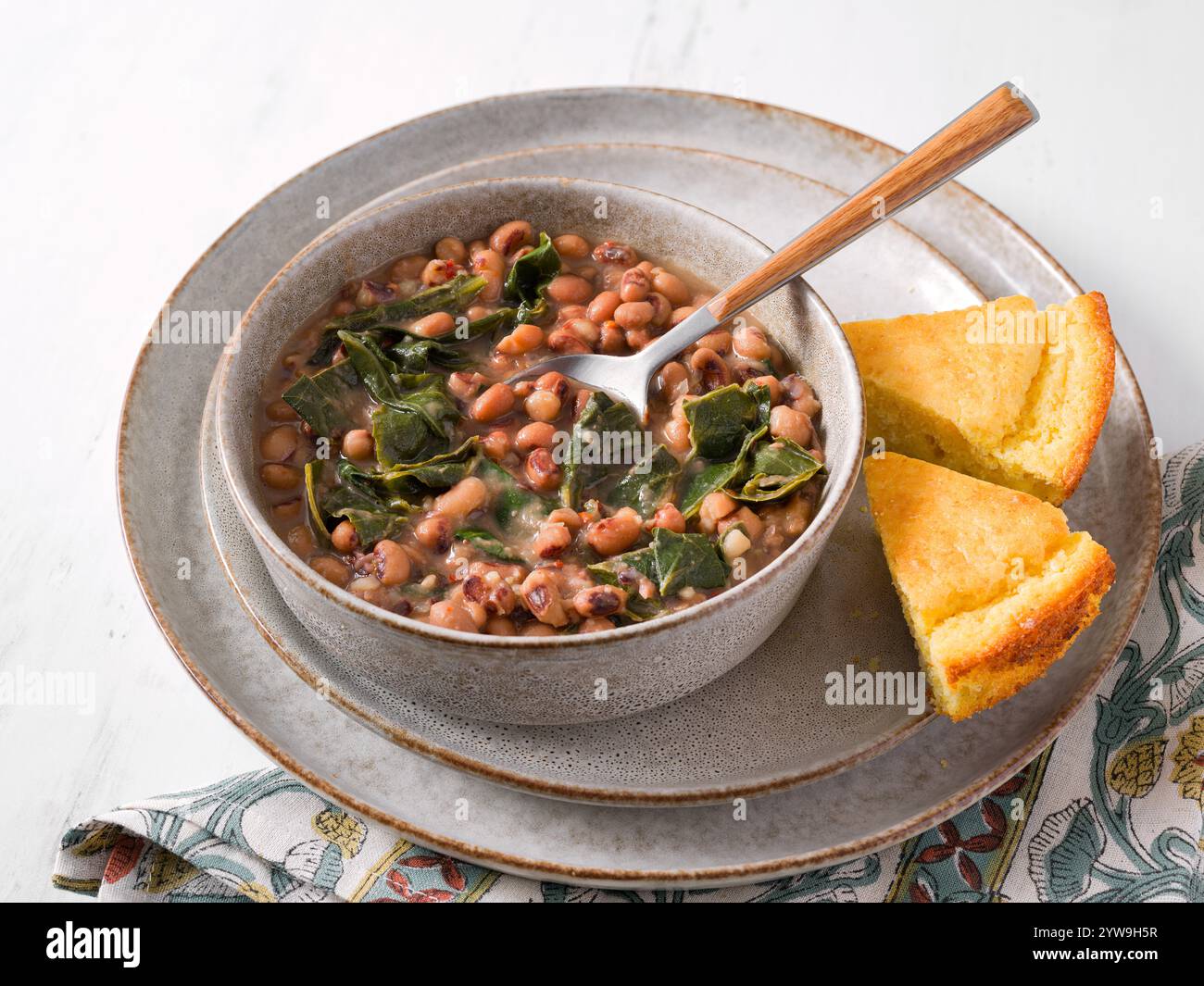Vista ad alto angolo dei piselli dagli occhi neri e dei verdi del colletto con due fette di pane di mais Foto Stock