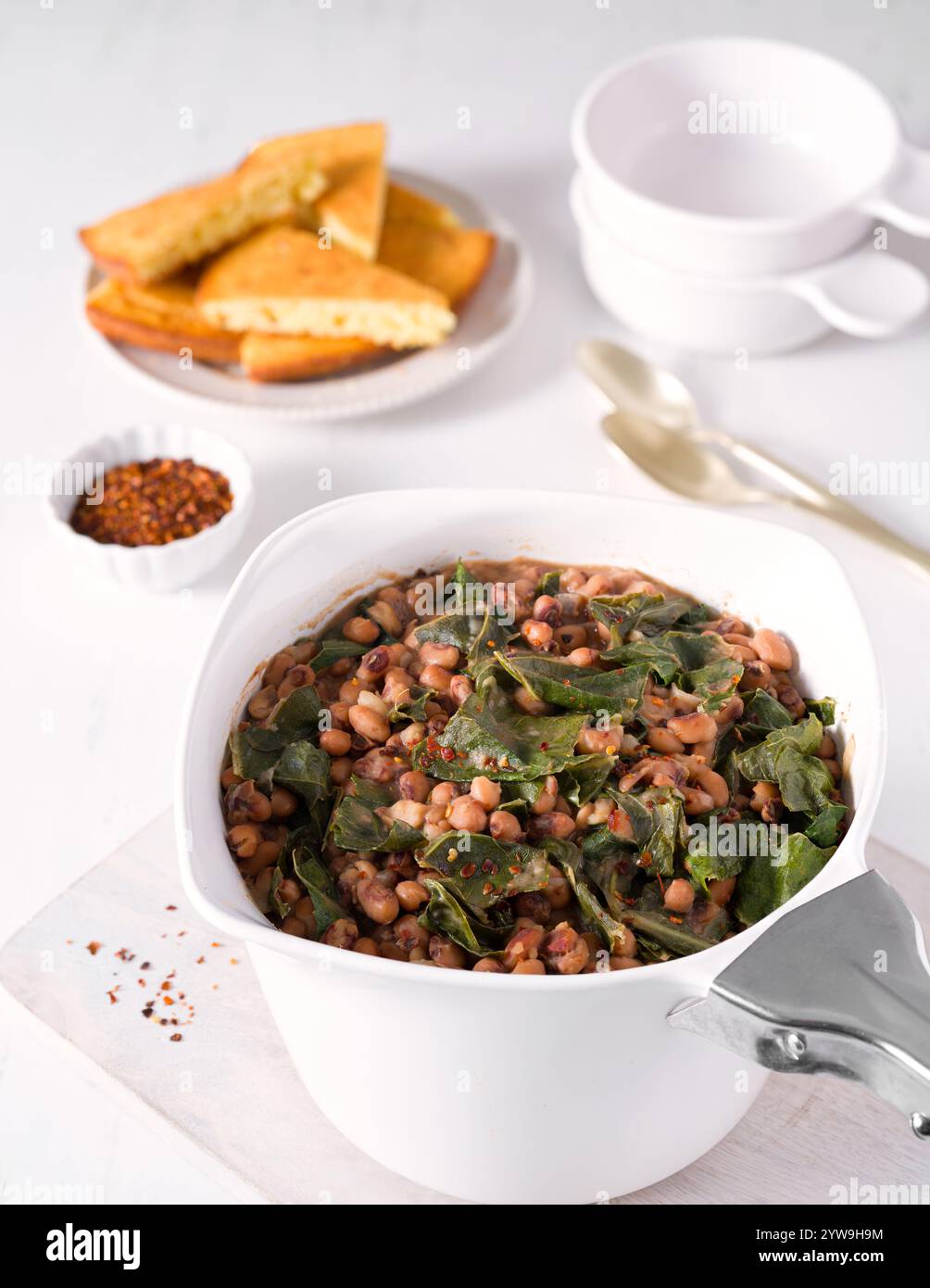 Piselli dagli occhi neri con verdi del colletto in un grande recipiente bianco con pane di mais a lato; tradizione del Capodanno meridionale degli Stati Uniti Foto Stock
