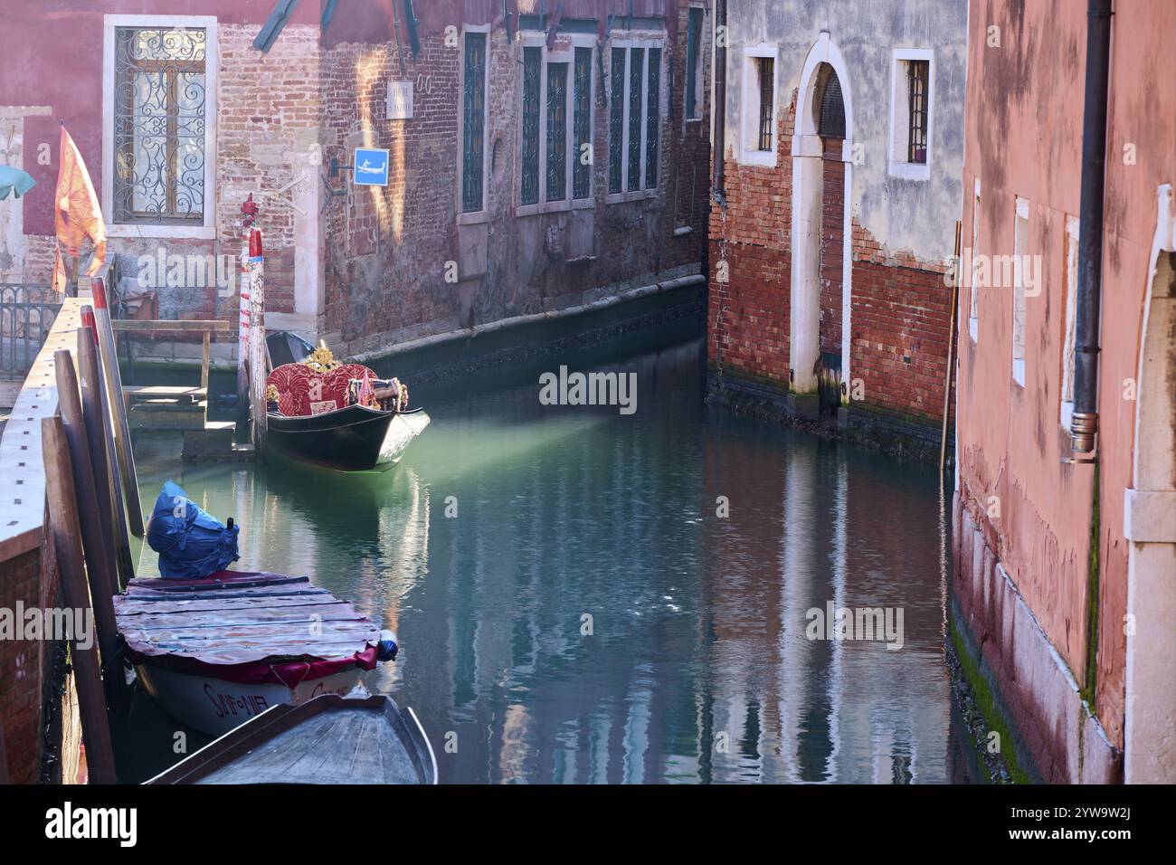 Vista da una gondola su un corso d'acqua a Venezia passando attraverso le case in una tranquilla e soleggiata mattinata d'inverno, Italia, Europa Foto Stock